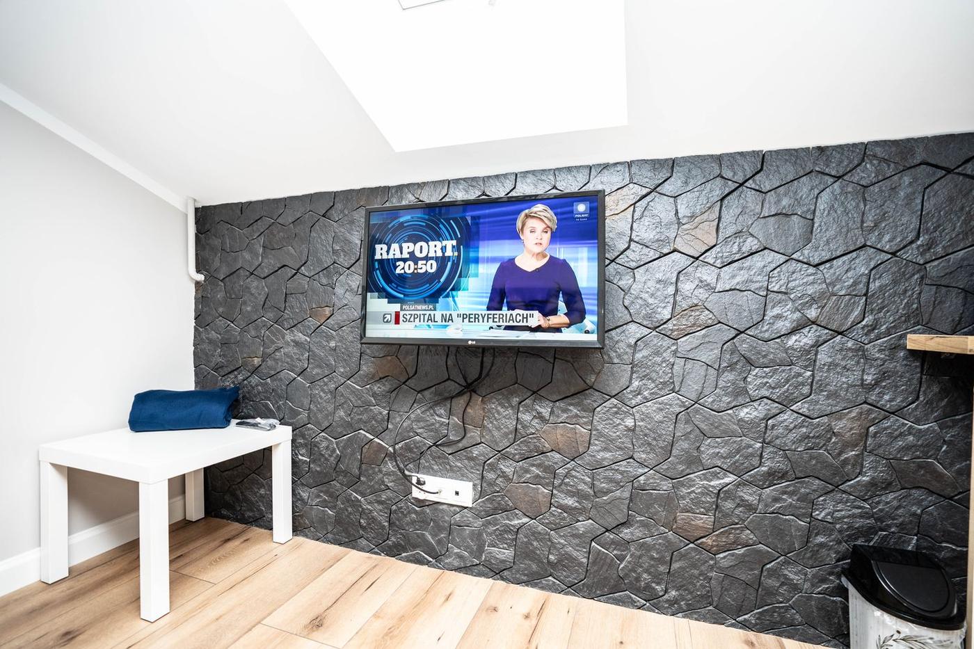 Telewizor na ścianie z ciemnego kamienia